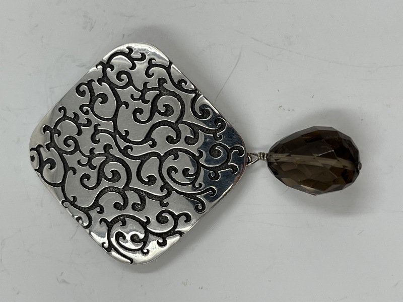 Brosje i sølv med sten.